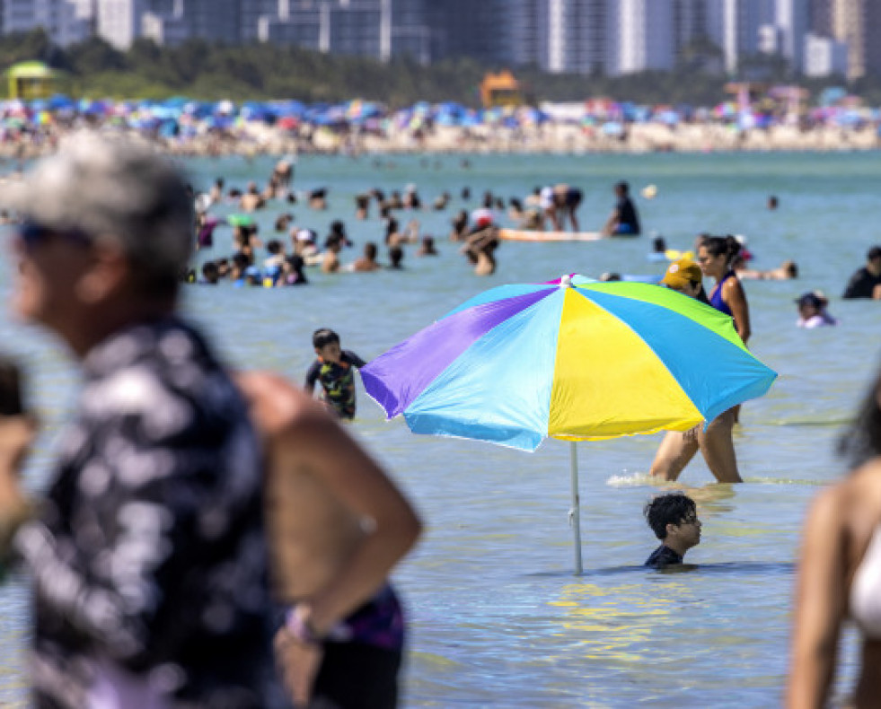 Un hombre planta su sombrilla en medio del mar en la playa de Miami, Florida, Estados Unidos @CRISTÓBAL HERRERA (EFE)