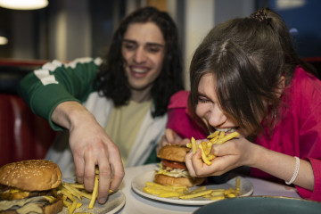 Amigos de tiro medio comiendo comida rapida de una manera divertida