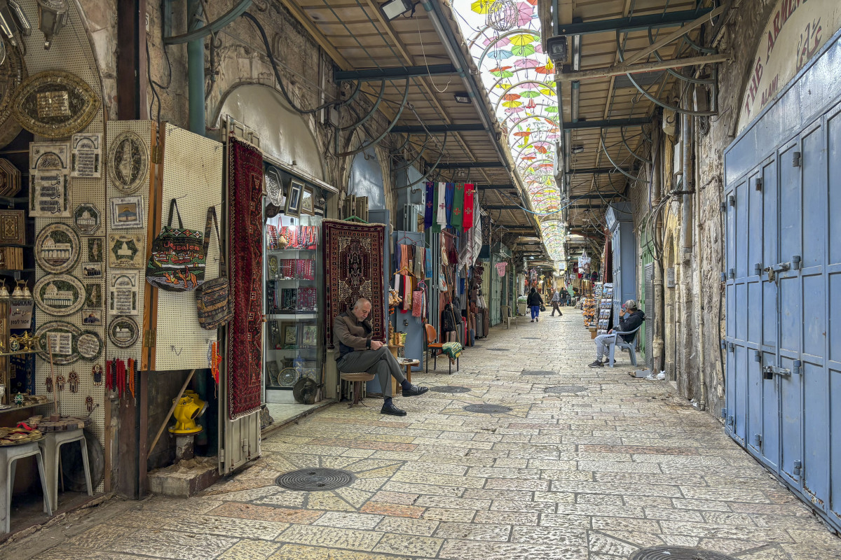 JERUSALÉN, 28/03/2024.- Es Semana Santa y la Ciudad Vieja de Jerusalén está prácticamente vacía por el impacto de la guerra en la Franja de Gaza: tiendas con pocos clientes y pocos peregrinos, mientras los palestinos cristianos, muchos residentes en Cisjordania, no han obtenido permisos para visitar la ciudad santa. Algunas tiendas tienen el cerrojo echado, también por ser el mes de Ramadán, y los vendedores hojean el periódico o toman café mientras gritan a los pocos turistas que pasean por la calle para que les compren algo. EFE/ Jorge Dastis